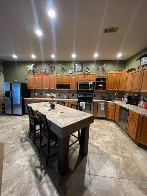 Modern kitchen with wooden cabinets, stainless steel appliances, and a large island. Hunting and Fishing Lodge.